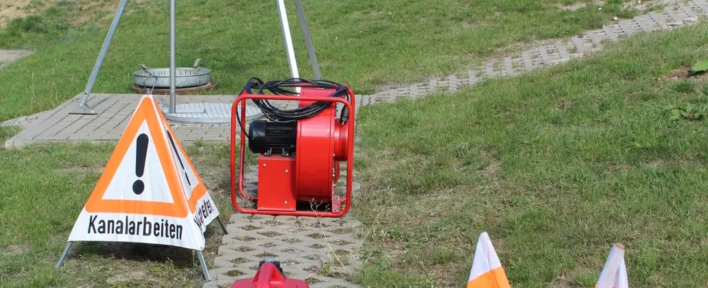 Kanalarbeiter vor Warnschild an einem Schacht – BVE Weimar